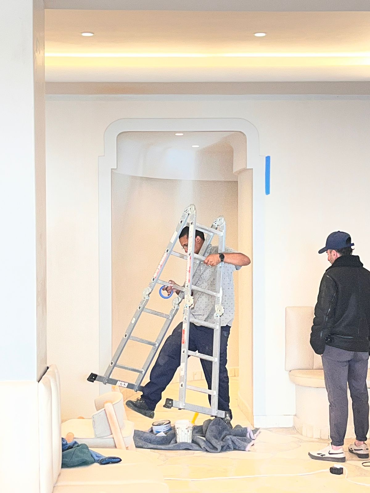 Interior renovation with a shaped archway and workers carrying a ladder