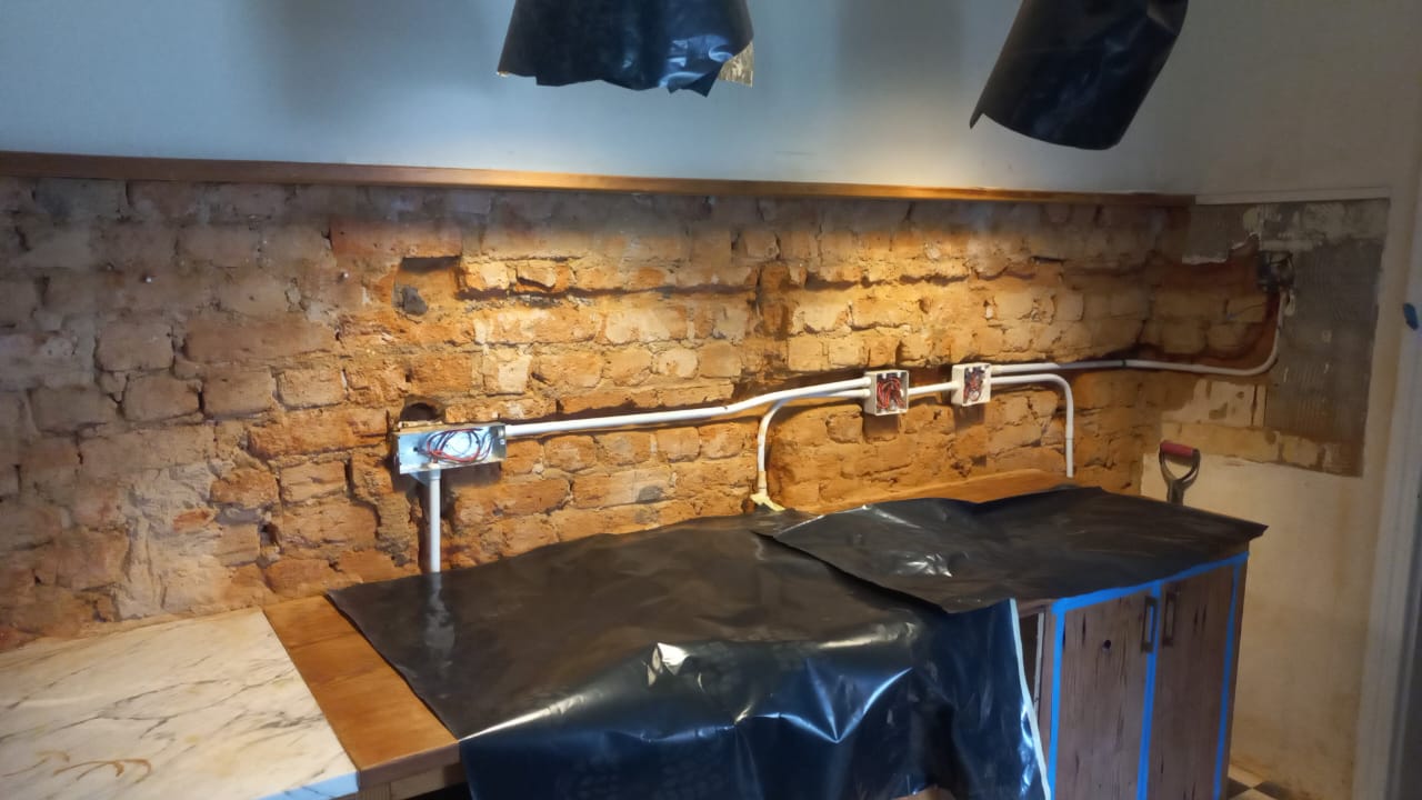 Kitchen countertop protected with sheeting below an exposed wall during renovation