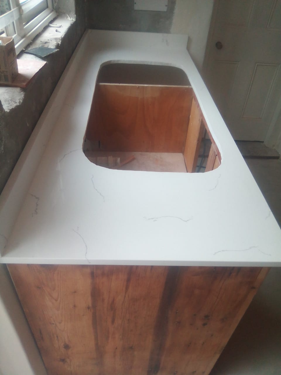 Close view of a white kitchen countertop with a sink opening