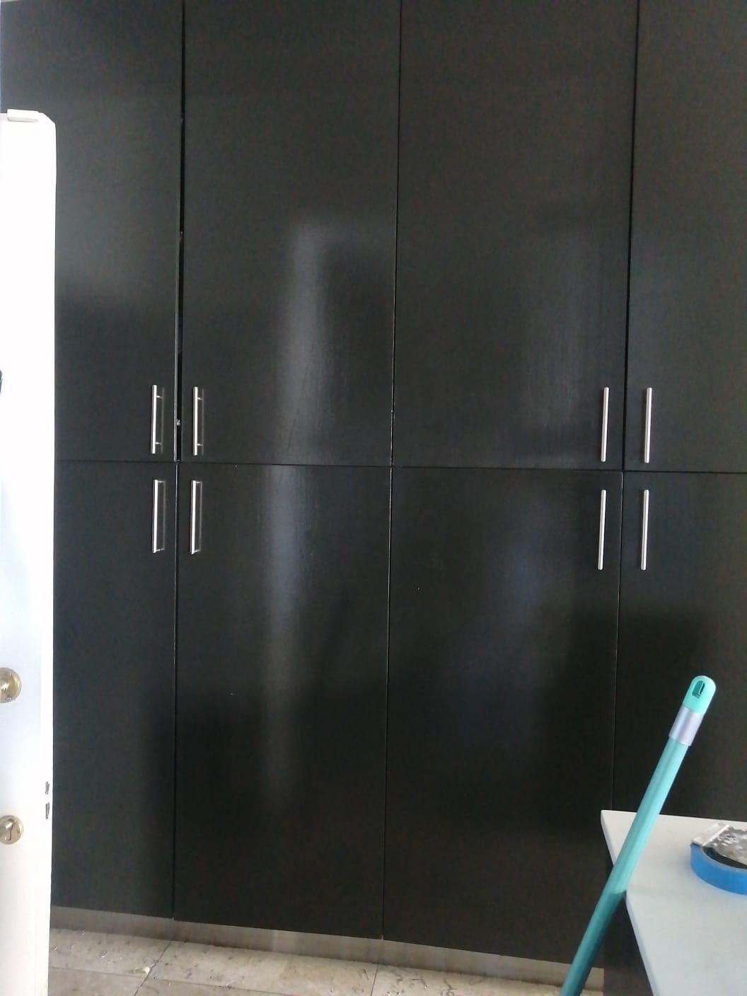 Dark full-height kitchen cupboard doors with metal handles