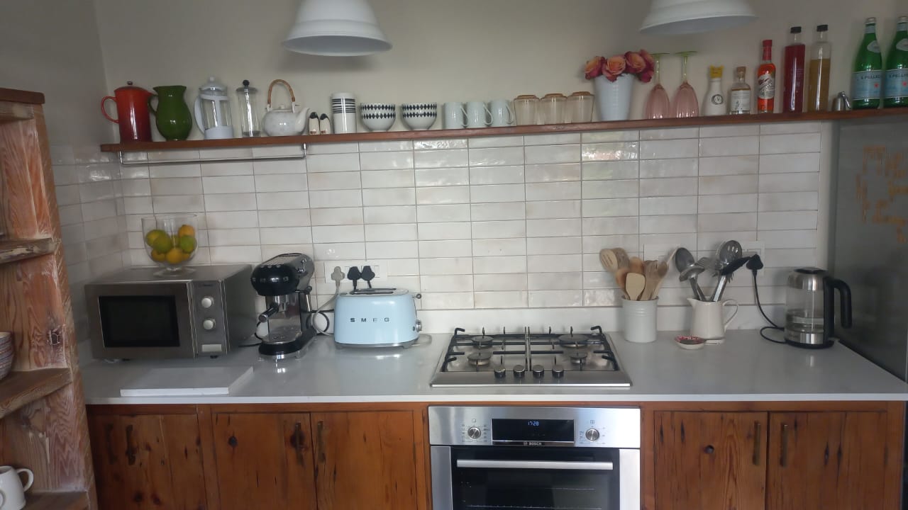 Kitchen with white tiled splashback, worktop and timber cupboards