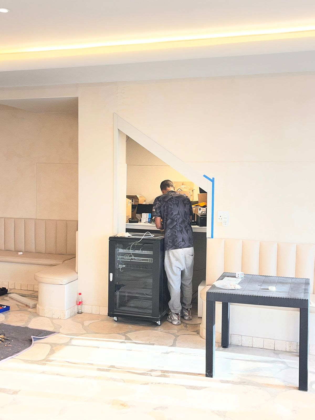 Lounge with built-in upholstered seating, stone flooring and installation work in progress