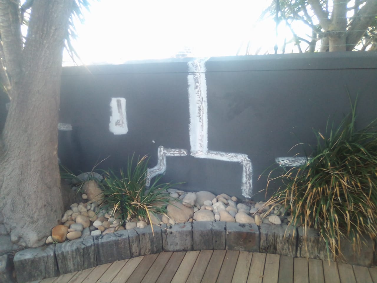 Garden wall with repaired vertical and stepped cracks highlighted by white filler
