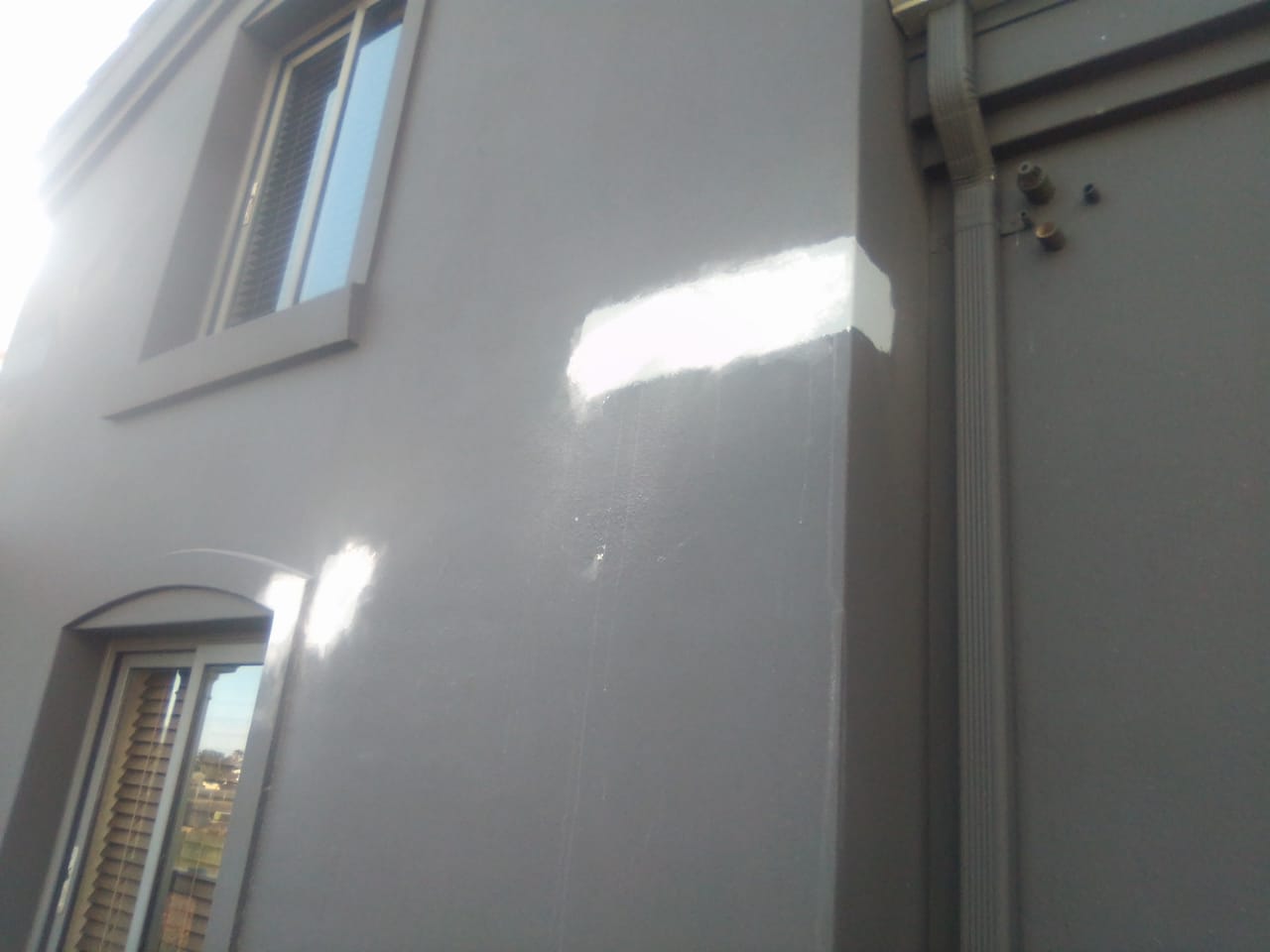 Grey exterior wall beside a window with white repair patches