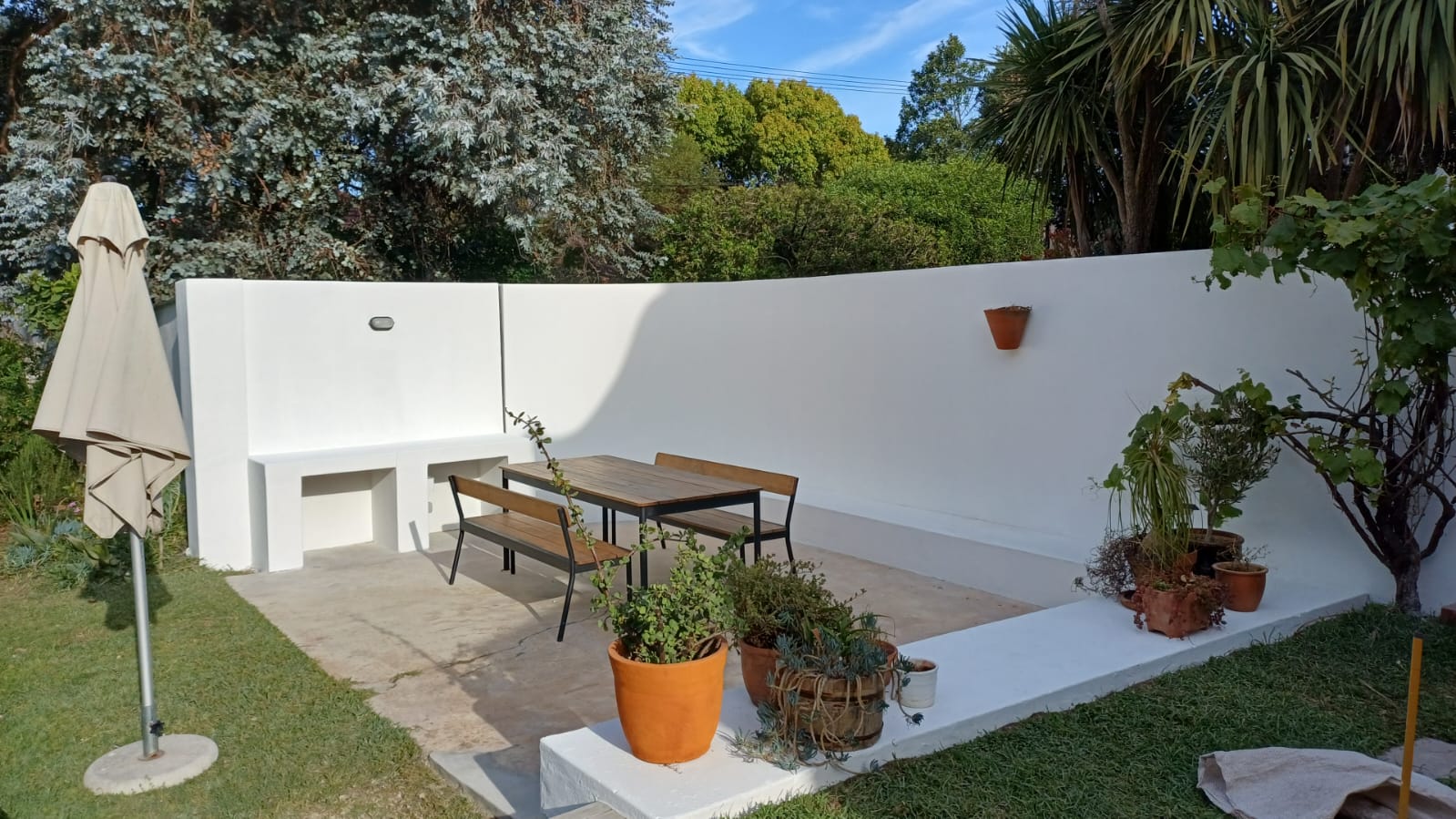Finished garden patio with white walls, built-in benches and a dining table