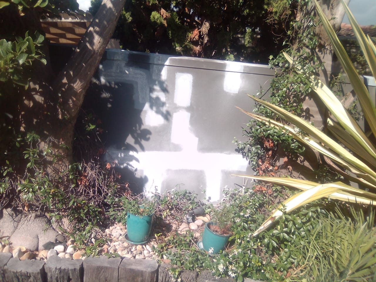 Garden wall with white repair patches before repainting