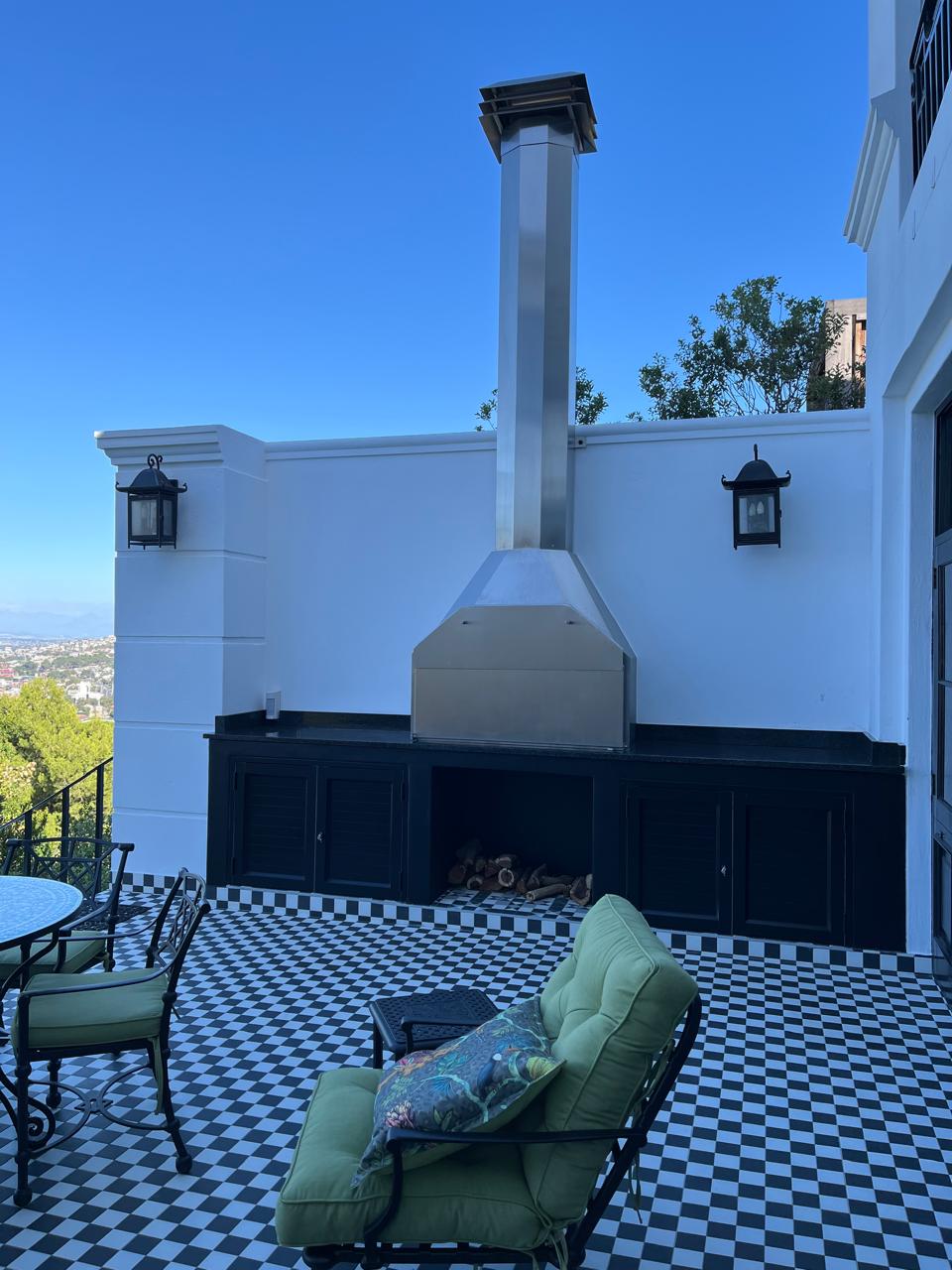 Black-and-white tiled terrace with a built-in braai and metal chimney