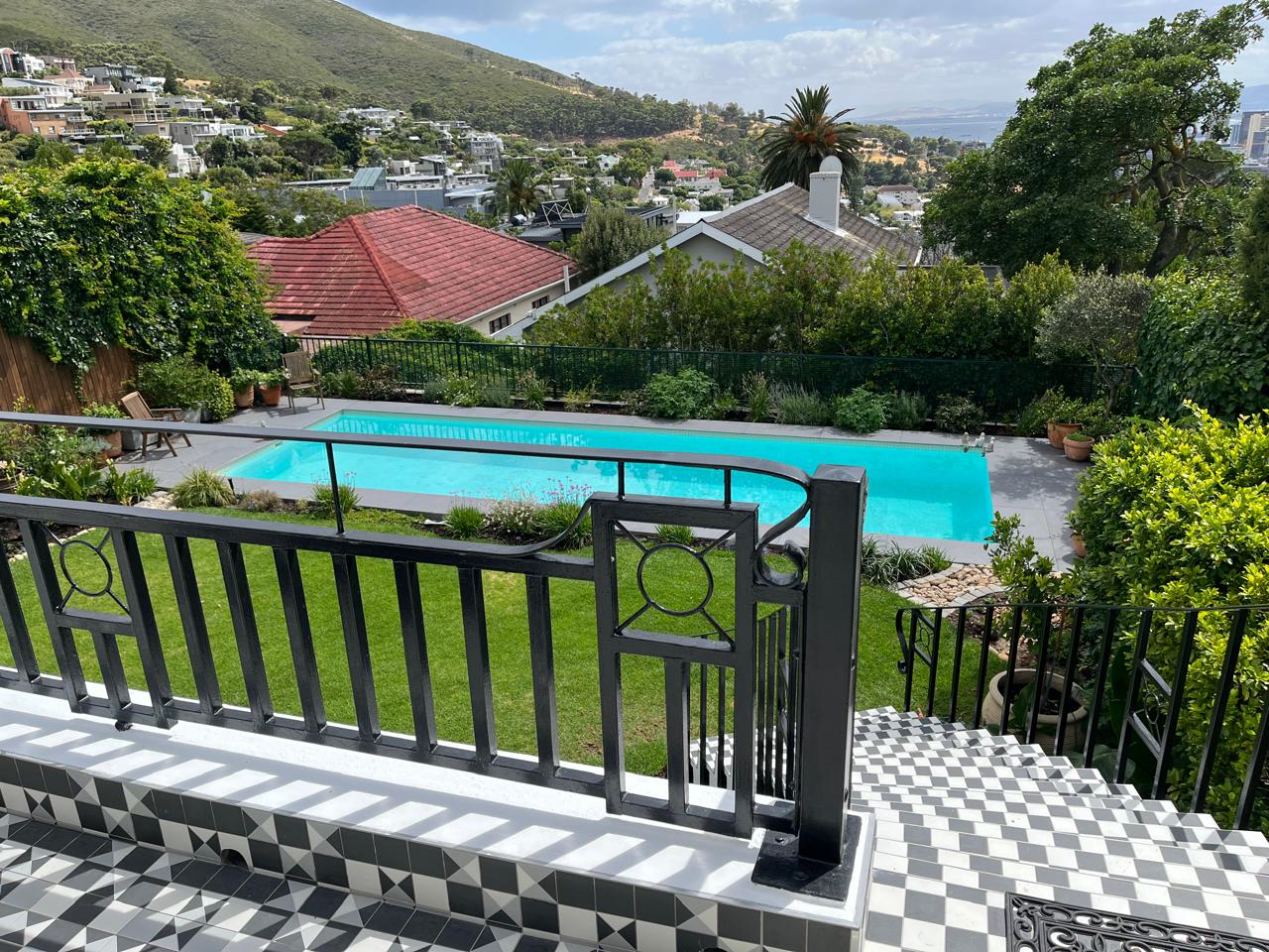 Swimming pool with grey paved surround and black-and-white patterned tiled steps