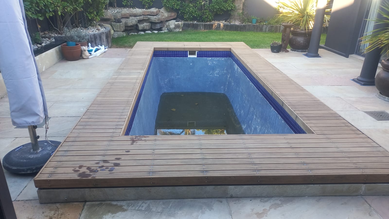 Completed timber decking surround around a drained swimming pool