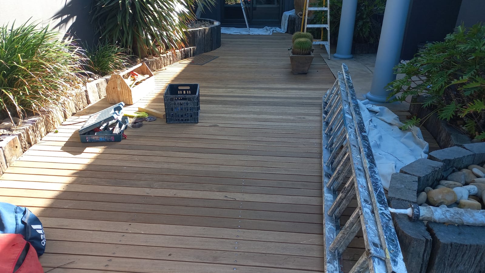New timber decking beside garden beds with tools and ladders during installation