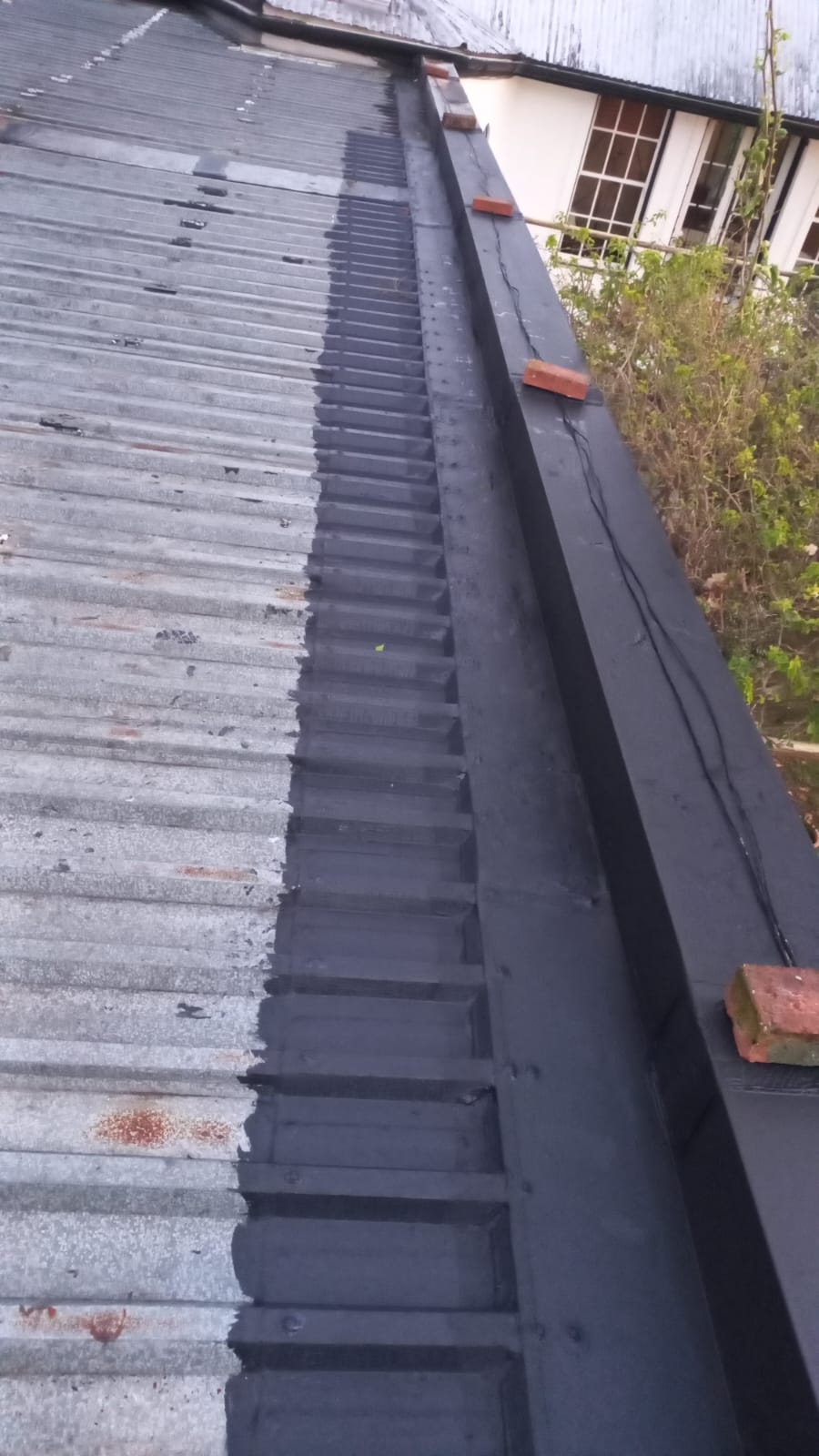 Dark waterproofing treatment along a corrugated roof edge