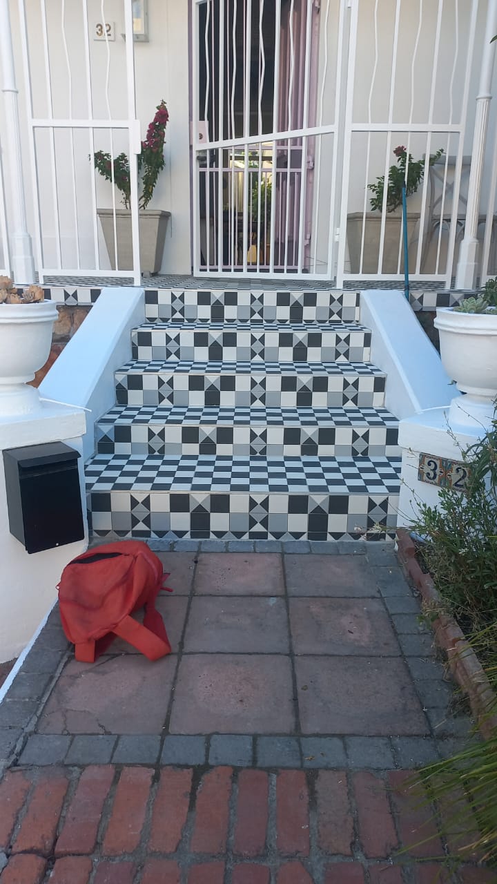Finished black-and-white patterned entrance steps leading to a white security gate