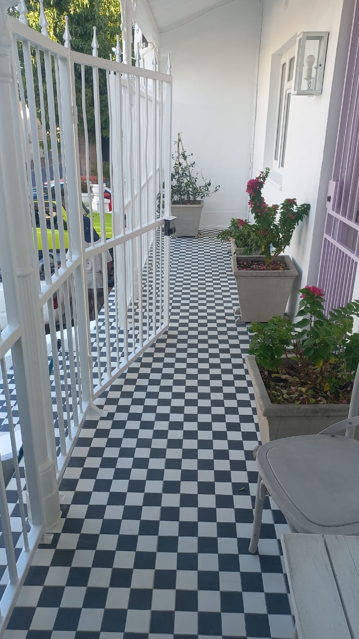 Black-and-white checkerboard veranda floor beside white railings and potted plants