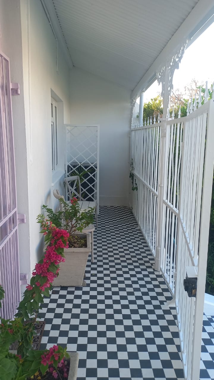 Long veranda with black-and-white checkerboard tiles, white railings and potted plants